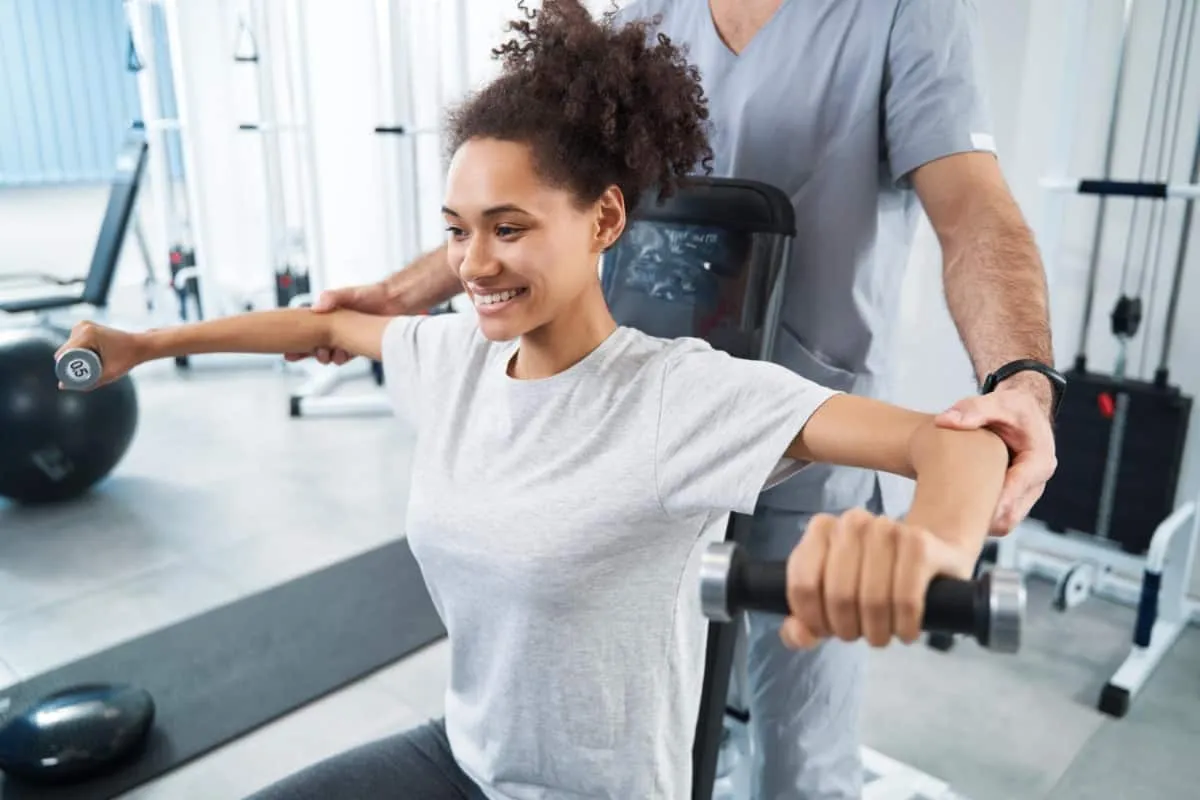 pacjent ćwiczy z fizjoterapeutą na sali rehabilitacyjnej