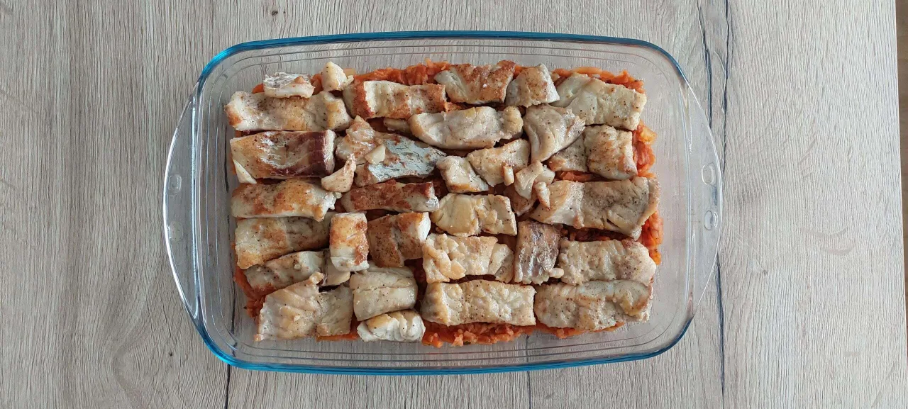 Pyszny obiad low carb: kawałki ryby ułożone na warzywach w szklanym naczyniu.