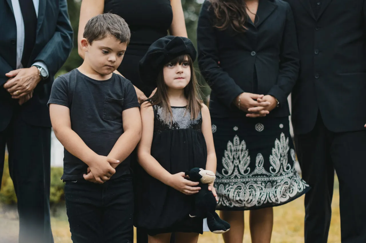 Dzieci w stonowanych ubraniach na pogrzebie