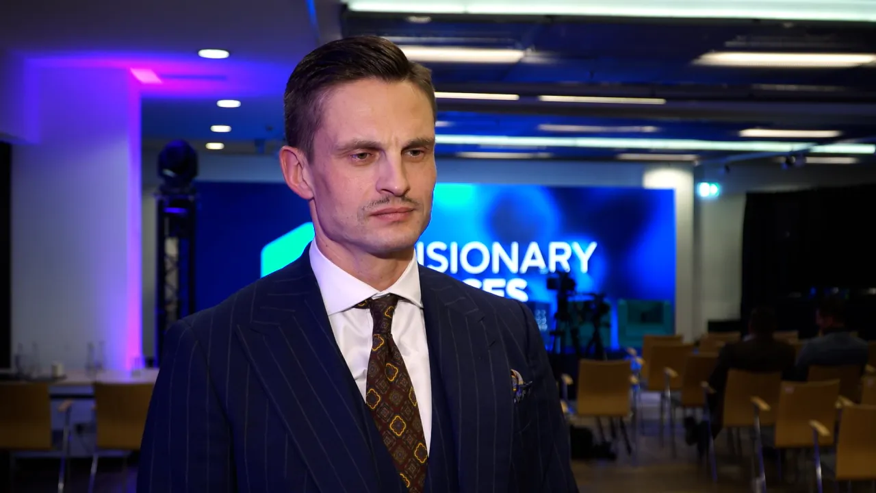 Mężczyzna w garniturze przed ekranem z napisem 