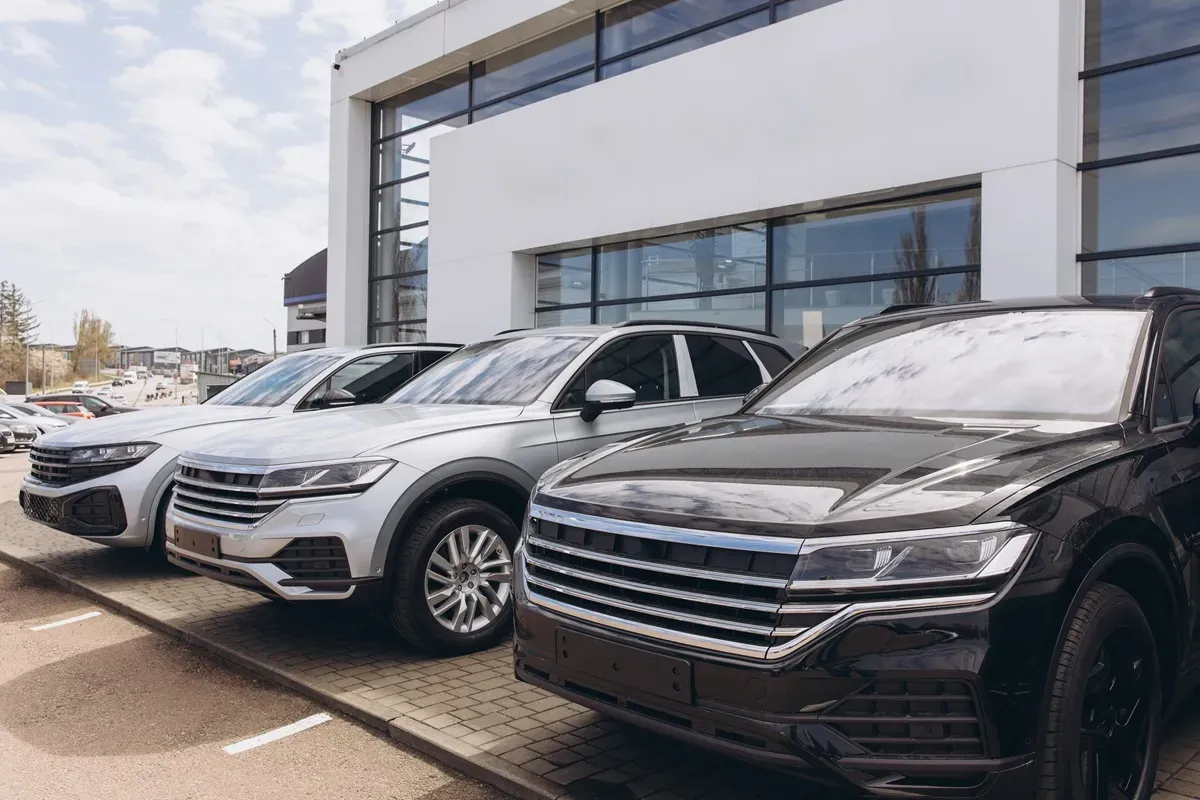 Nowe samochody na firmę, lśniące czarne i srebrne SUV-y czekają na odbi&oacute;r.