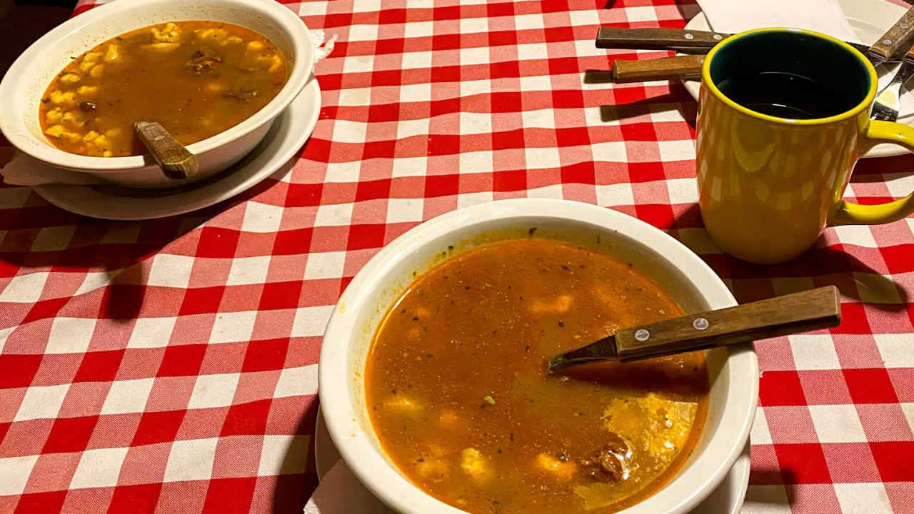 Dwa talerze gulaszu węgierskiego i żółty kubek kawy na czerwono-białej kratce. Ciekawe, ile forintów kosztuje obiad na Węgrzech?