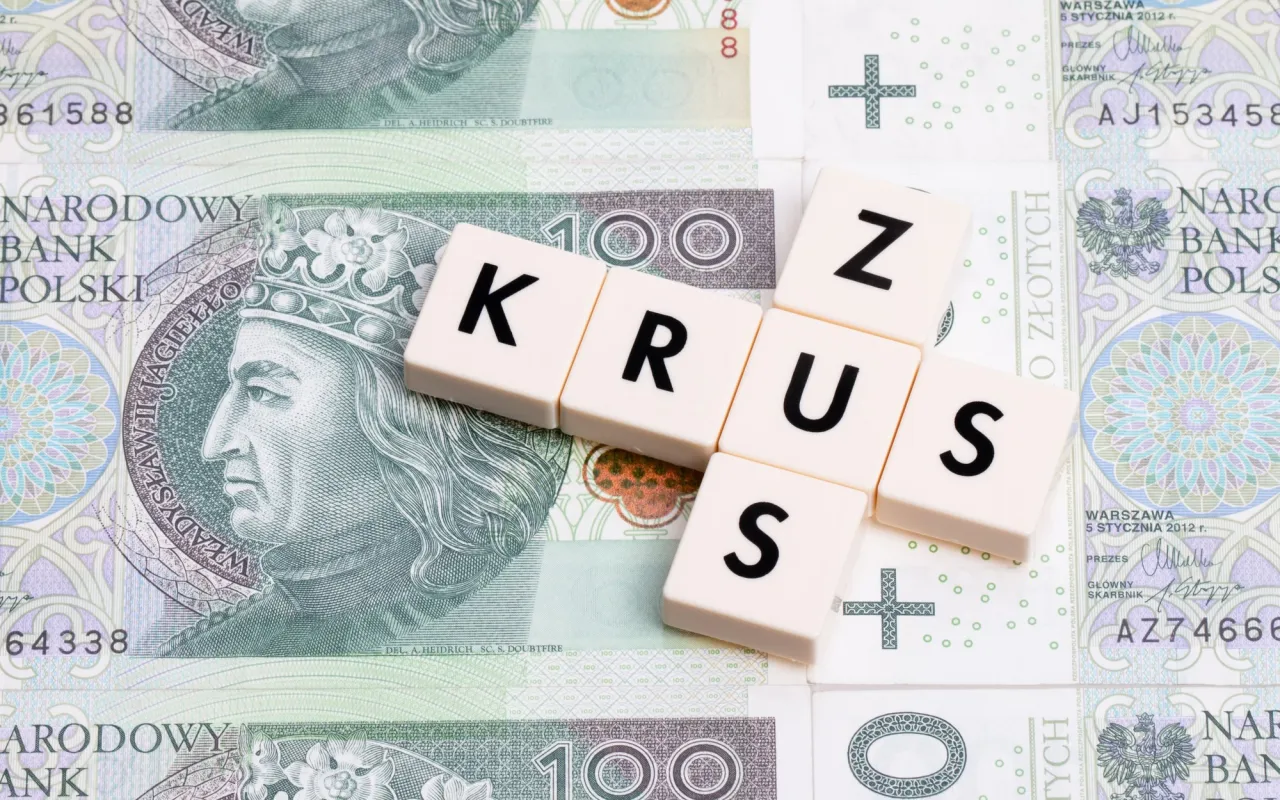 Litery KRUS ułożone na banknotach 100 zł. Czy chorobowe wlicza się do emerytury KRUS?
