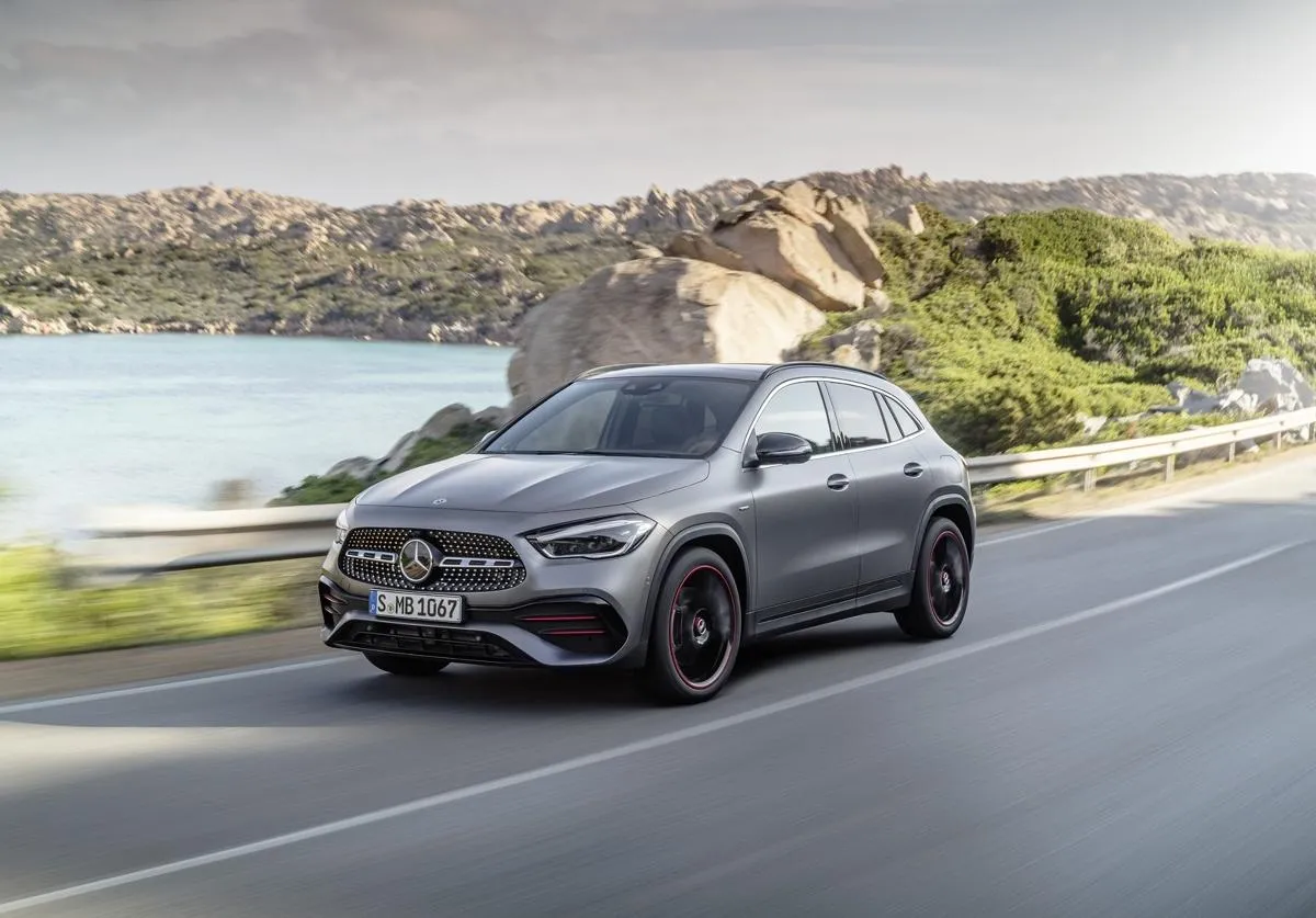 Szary Mercedes-Benz GLA AMG pędzi malowniczą drogą nad morzem.