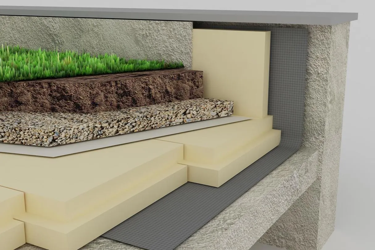 Przekrój zielonego dachu płaskiego. Widoczna warstwa trawy, ziemi, żwiru, izolacji termicznej i membrany.