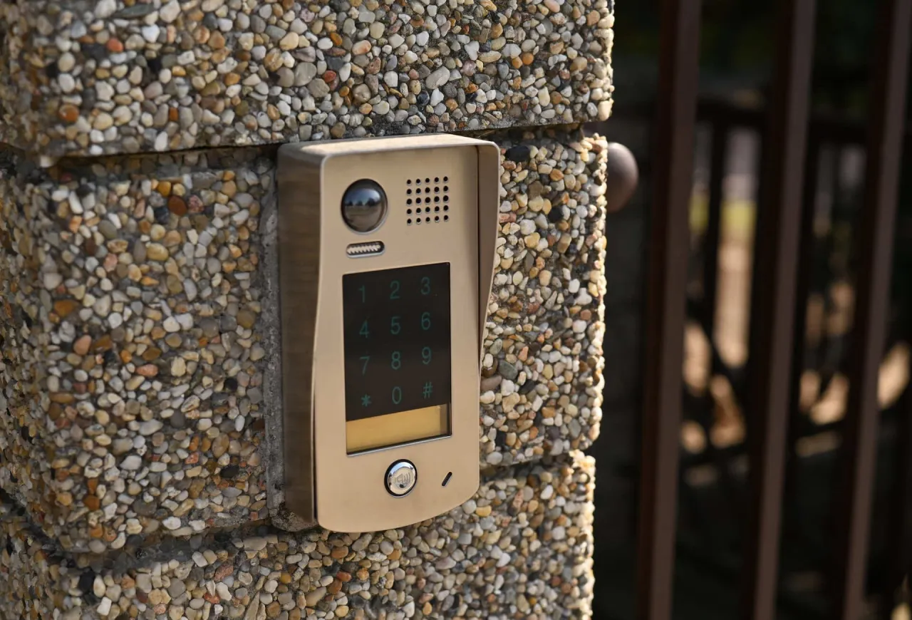 Domofon z kamerą i klawiaturą numeryczną na kamiennym słupku. Dowiedz się, ile kosztuje montaż domofonu w domu jednorodzinnym.