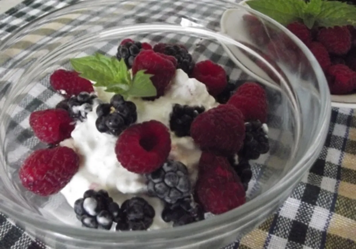 miseczka serka wiejskiego z r&oacute;żnymi owocami leśnymi