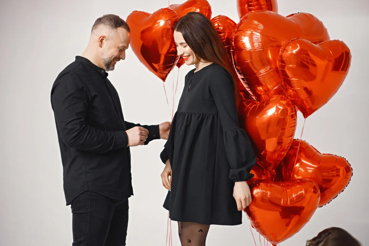 Para walentynkowa z bukietem czerwonych balonów w kształcie serc. Idealne prezenty na walentynki.