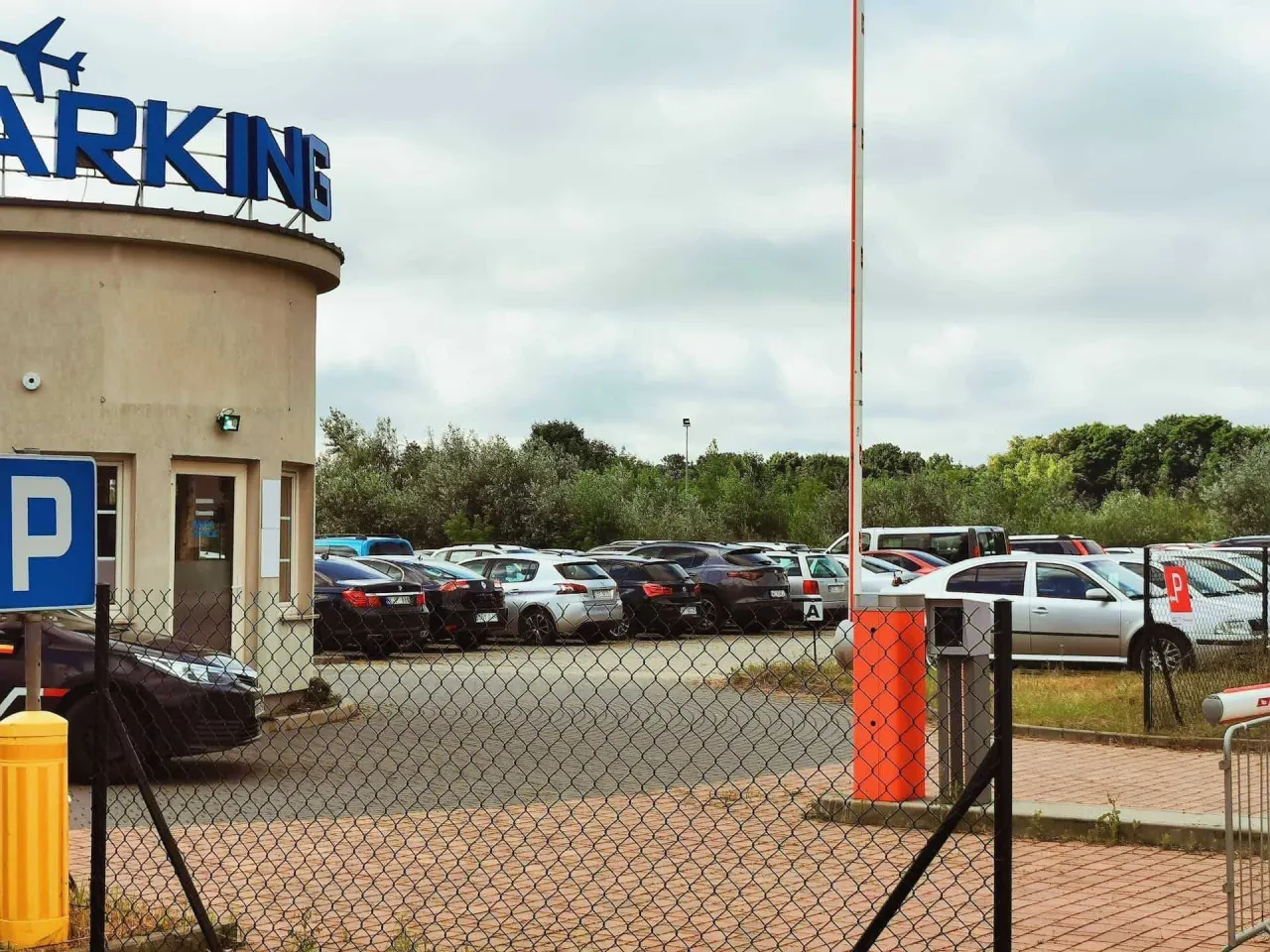 Zastanawiasz się, ile kosztuje parking na lotnisku w Warszawie? Na zdjęciu widać parking z szlabanem i samochodami.