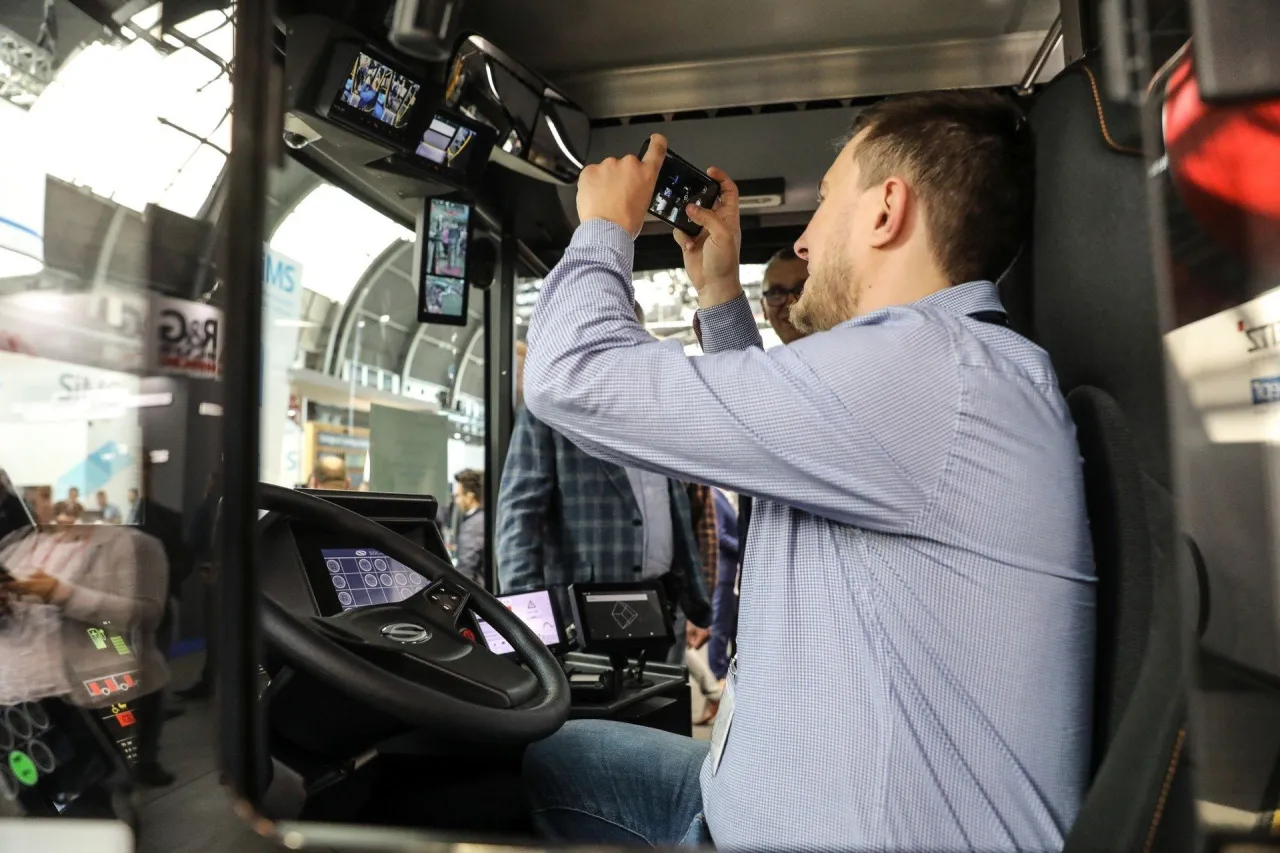 Mężczyzna w niebieskiej koszuli robi zdjęcie nowoczesnego kokpitu autobusu. Zastanawia się, ile zarabia kierowca autobusu PKS.