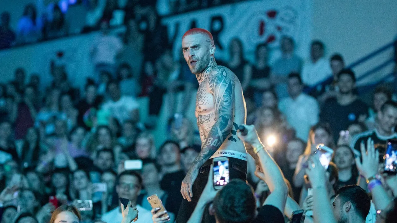 Artysta z tatuażami na scenie, tłum nagrywa telefonami. Fani zastanawiają się, ile trwa koncert Maty.