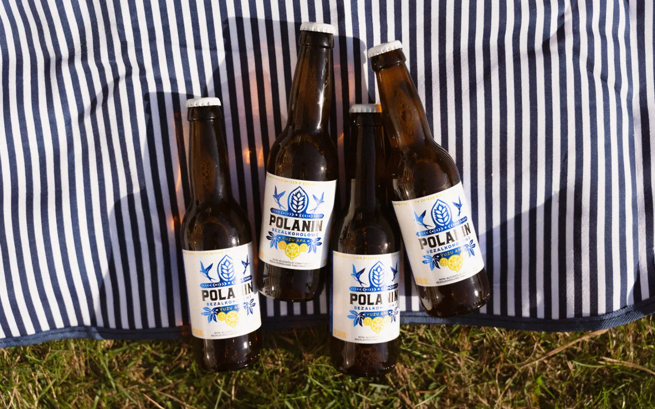 Cztery butelki piwa bezalkoholowego Polanin Yuzu APA leżą na kocu w paski. Zastanawiasz się, ile kalorii ma piwo?