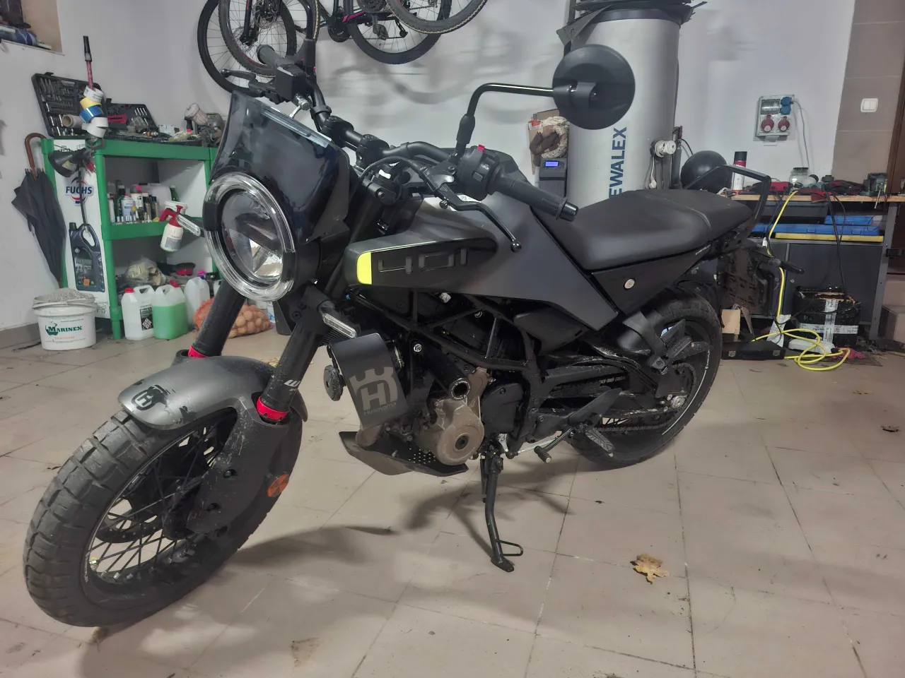 Czarny motocykl Husqvarna Svartpilen 250 stoi w garażu, gotowy do jazdy.