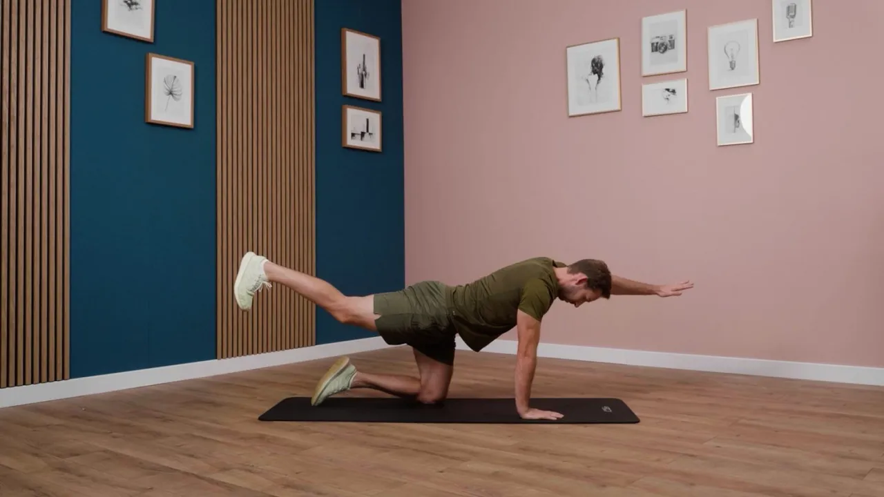 Mężczyzna na macie wykonuje ćwiczenie na stabilizację tułowia, które jest częścią treningu obwodowego.