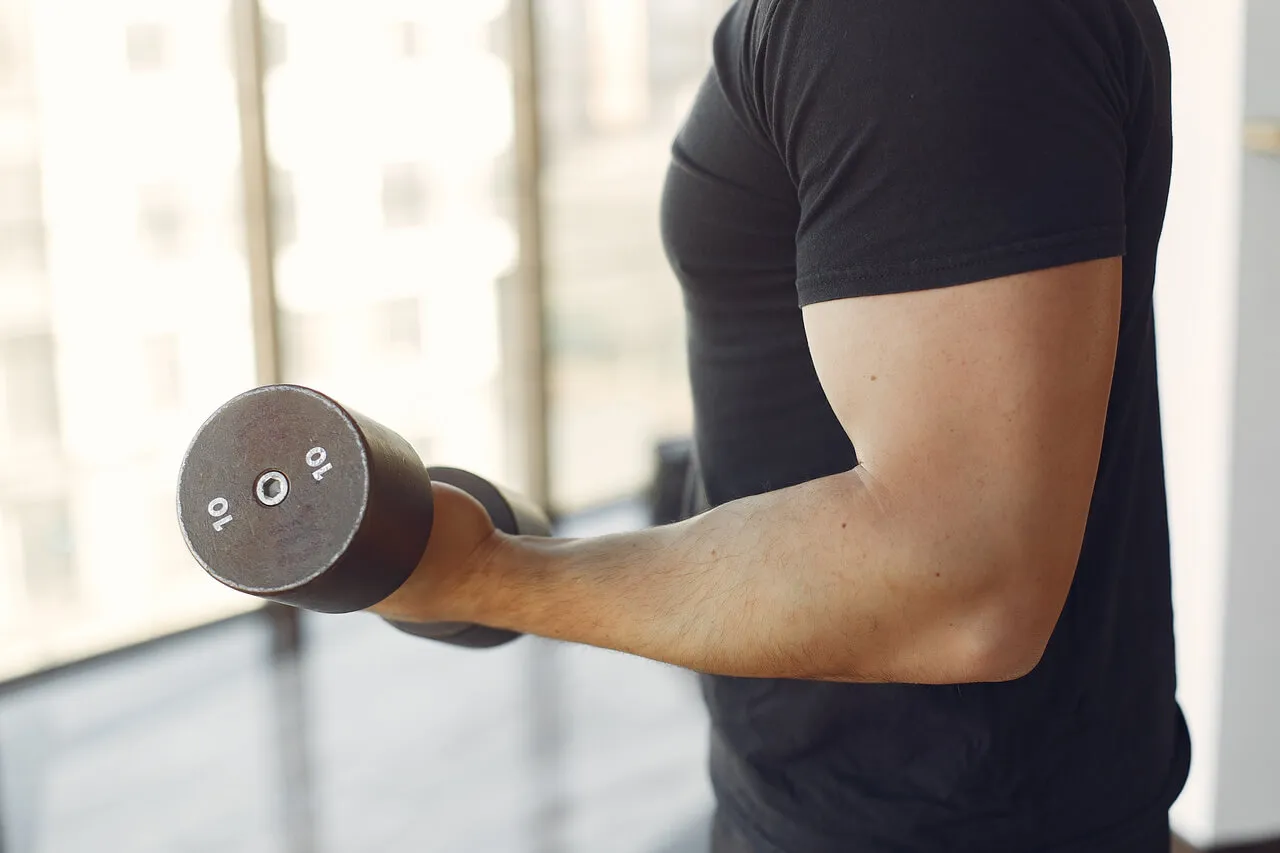 Mężczyzna ćwiczy biceps z hantlem 10 kg. Zastanawiasz się, ile razy w tygodniu ćwiczyć biceps?