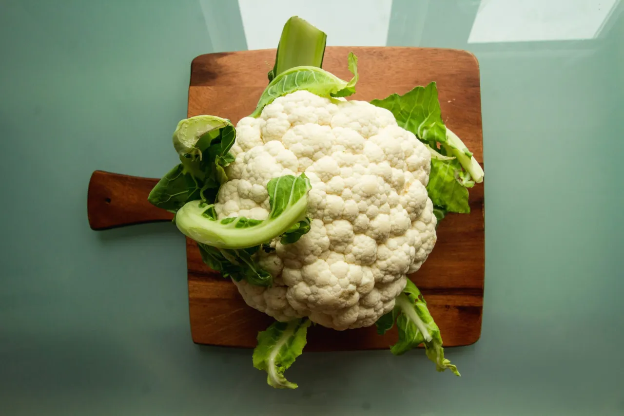 Cauliflower on a wooden board. Zastanawiasz się, czy pies może jeść kalafior? Tak, w małych ilościach i ugotowany.
