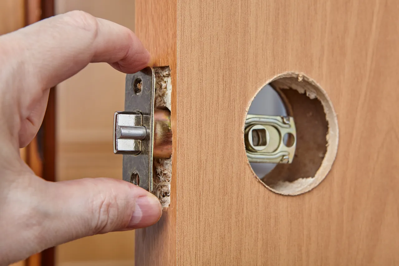 ślusarz wymienia zamek w drzwiach