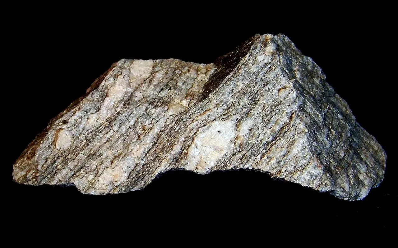 Skała metamorficzna z widocznymi żyłkami kwarcu i feldspatu, świadectwo procesów geologicznych, które doprowadziły do powstania Sudetów.