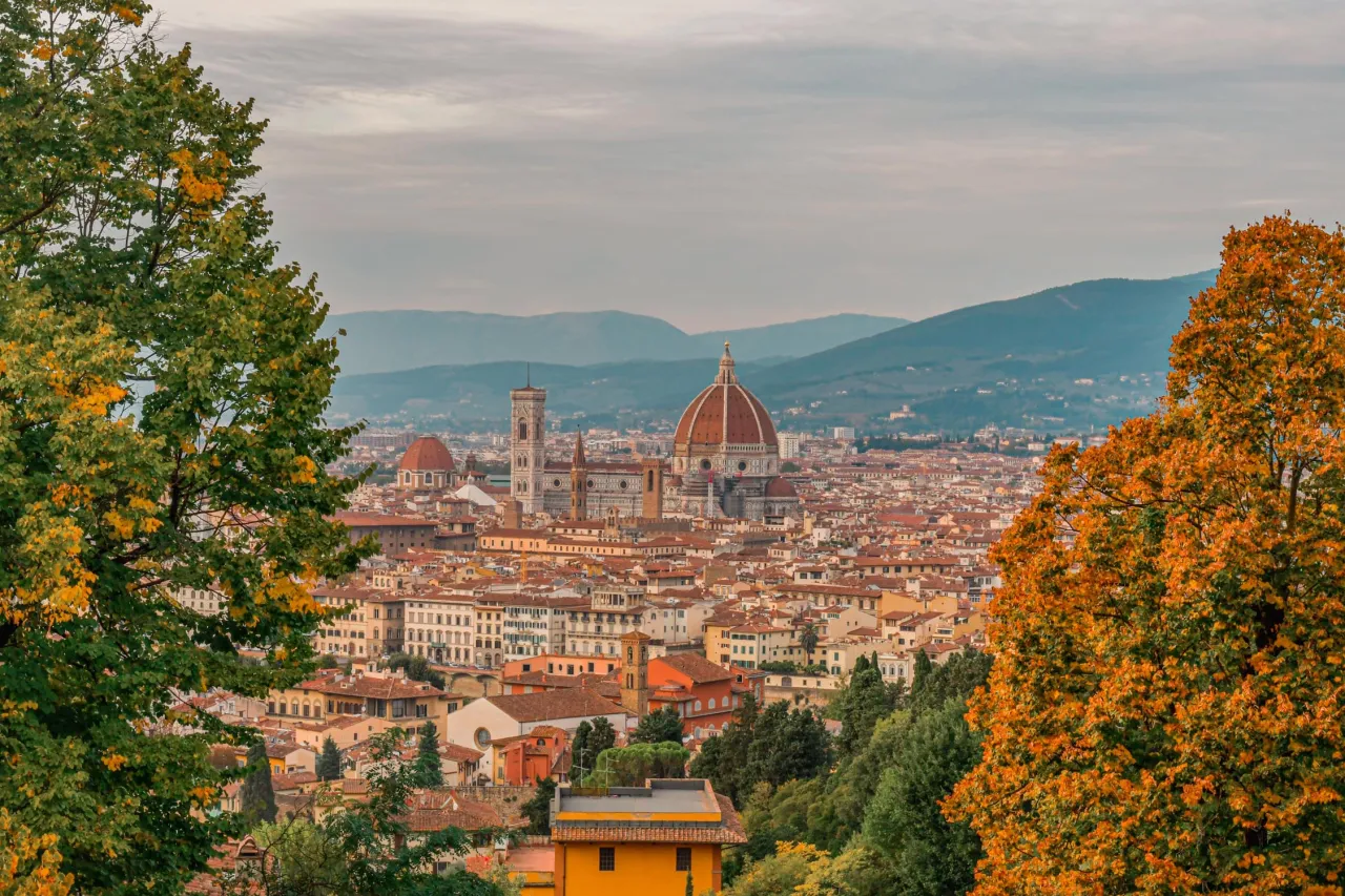 Florencja jesienią, z kopułą katedry i wieżą, otoczona drzewami w złotych barwach. Jedno z najpiękniejszych miejsc na wakacje na świecie.