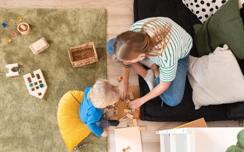 rodzic bawiący się z małym dzieckiem na podłodze klockami