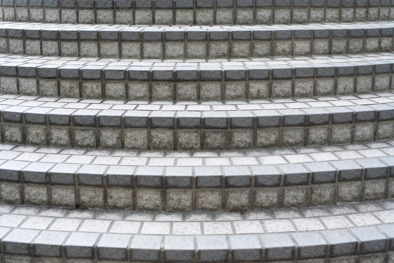 Schody z kostki brukowej, szare, z widocznymi fugami. Zastanawiasz się, ile kosztują schody z kostki brukowej?