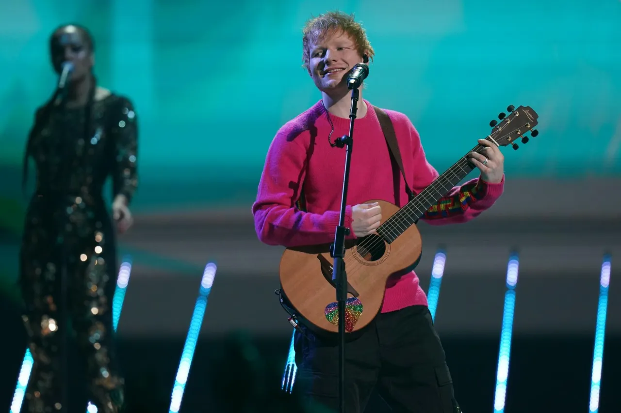 Ed Sheeran w r&oacute;żowym swetrze gra na gitarze. Zastanawiasz się, ile Ed Sheeran bierze za koncert?
