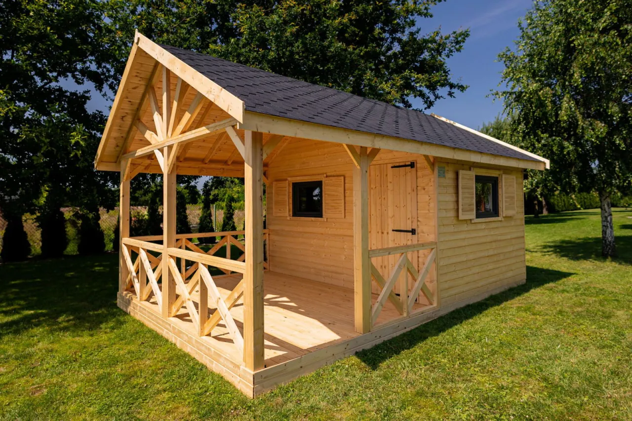 Drewniany domek na działkę ROD z werandą i ozdobną balustradą. Idealne miejsce na wypoczynek wśród zieleni.