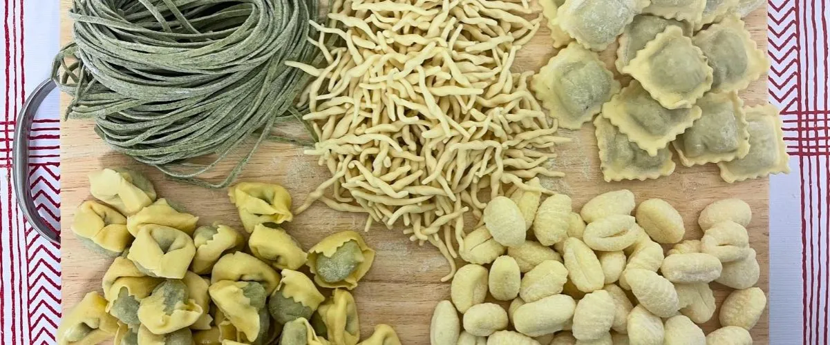Frische Pasta neben trockener Pasta auf einem Holztisch