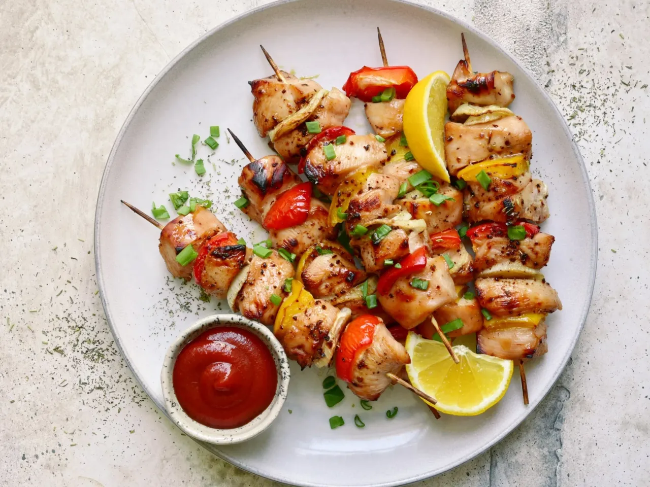 Pyszne szaszłyki z kurczaka z papryką i cebulą, pieczone w piekarniku, podane z cytryną i ketchupem.