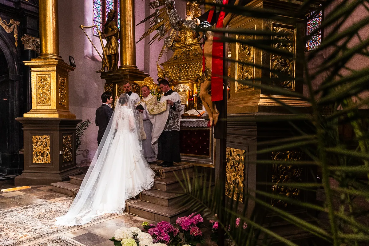Para młoda przed ołtarzem, ksiądz udziela błogosławieństwa. Zastanawiasz się, ile bierze fotograf za wesele?
