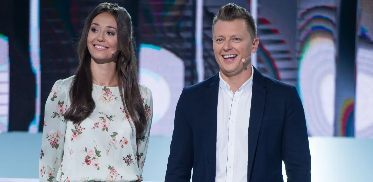 Uśmiechnięta para na scenie, ona w kwiecistej sukience, on w marynarce. Czyżby szykowali się do gry w koło fortuny kto ubiera?