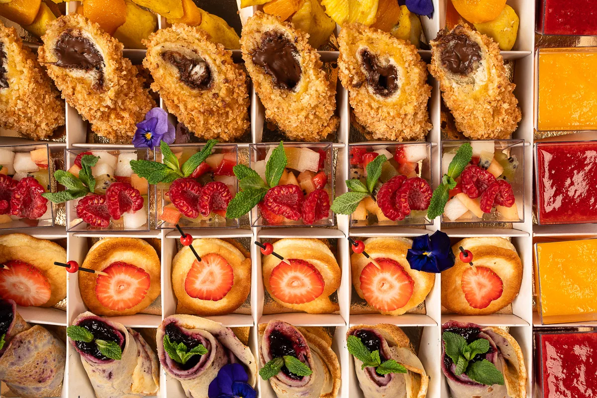 Catering na urodziny: słodkie przekąski, owoce i desery w pudełkach.