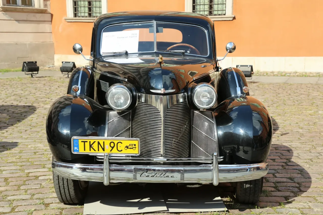Czarny Cadillac Fleetwood Imperial z 1938 roku, pojazd powyżej 40 lat ustawą, błyszczy na bruku.
