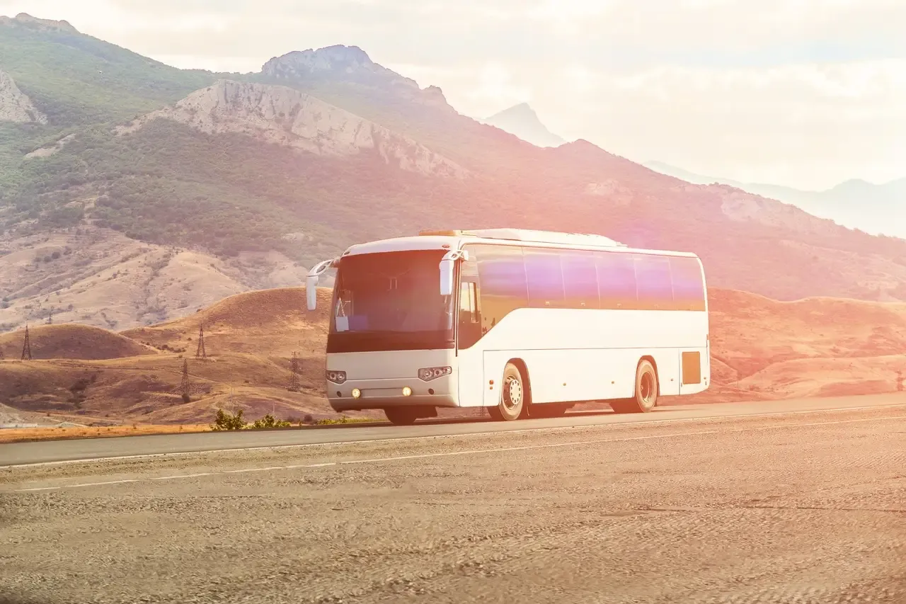 Biały autokar PKS jedzie malowniczą trasą. Zastanawiasz się, ile zarabia kierowca autobusu PKS?