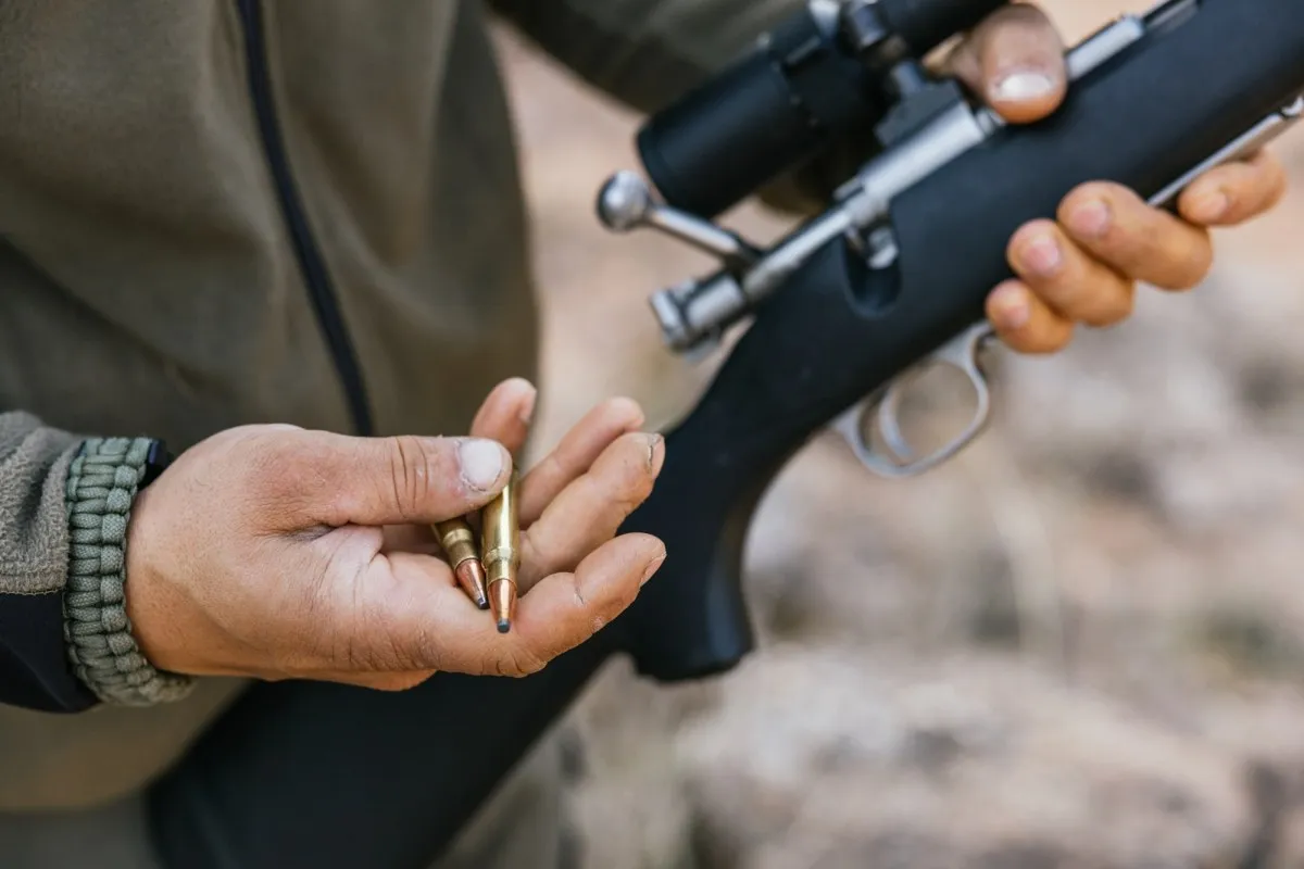 Myśliwy trzyma naboje i karabin. Czy myśliwi przechodzą psychotesty?