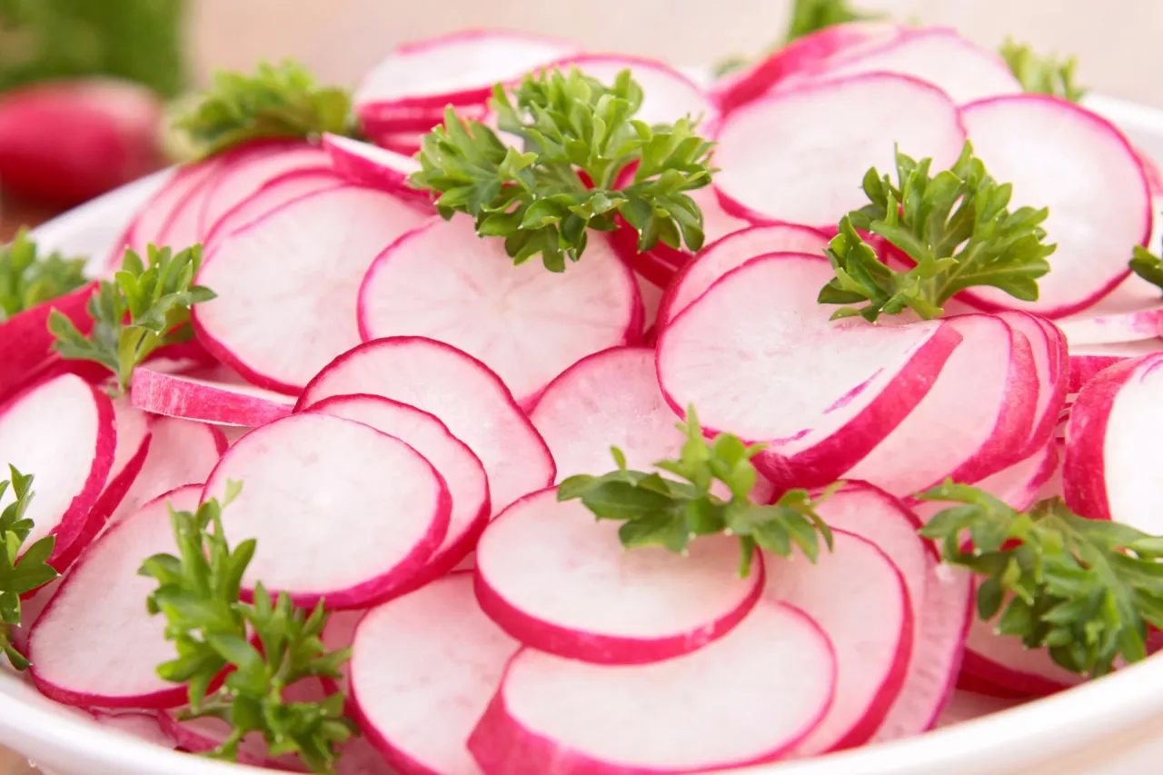 Talerz pełen plasterk&oacute;w rzodkiewki, ozdobiony natką pietruszki. Idealna przekąska, zastanawiasz się, ile rzodkiewek dziennie można zjeść?