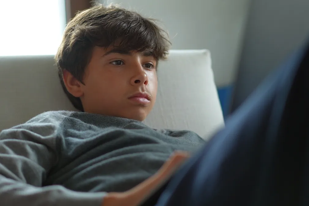 Nastolatek w wieku 13-15 lat zamyślony w swoim pokoju