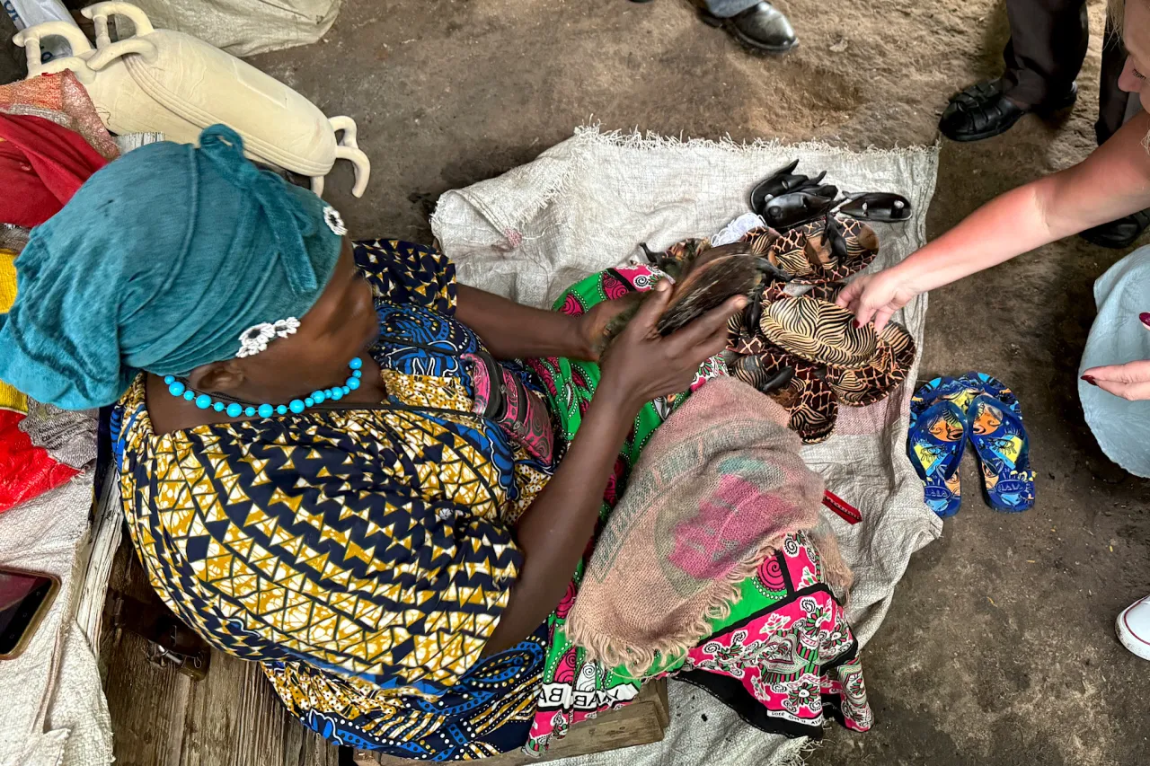 Kobieta w tradycyjnym stroju prezentuje ręcznie robione klapki z motywami zwierzęcymi – idealne pamiątki, co można przywieźć z Kenii.