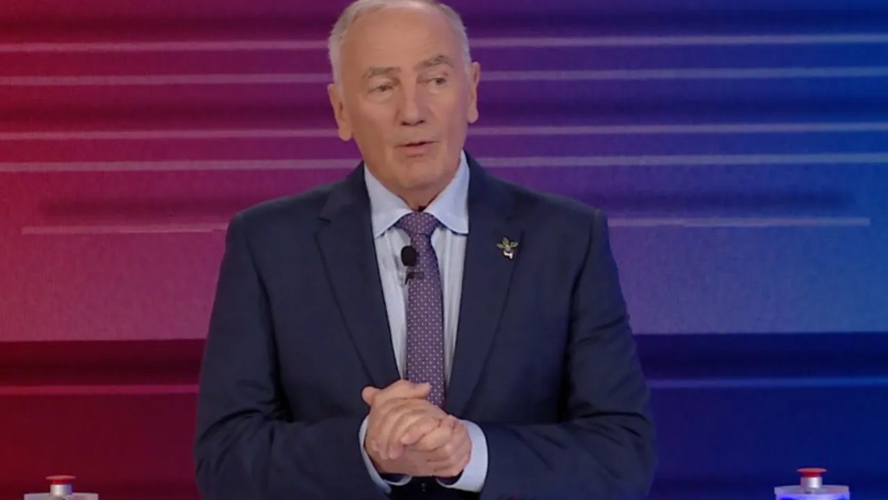 Mężczyzna w garniturze, prowadzący Familiadę od kiedy, z dłońmi złożonymi na piersi.