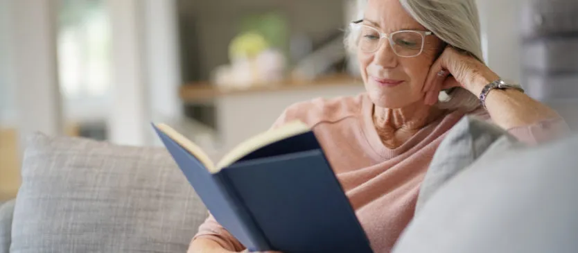 Osoba starsza czytająca książkę w okularach