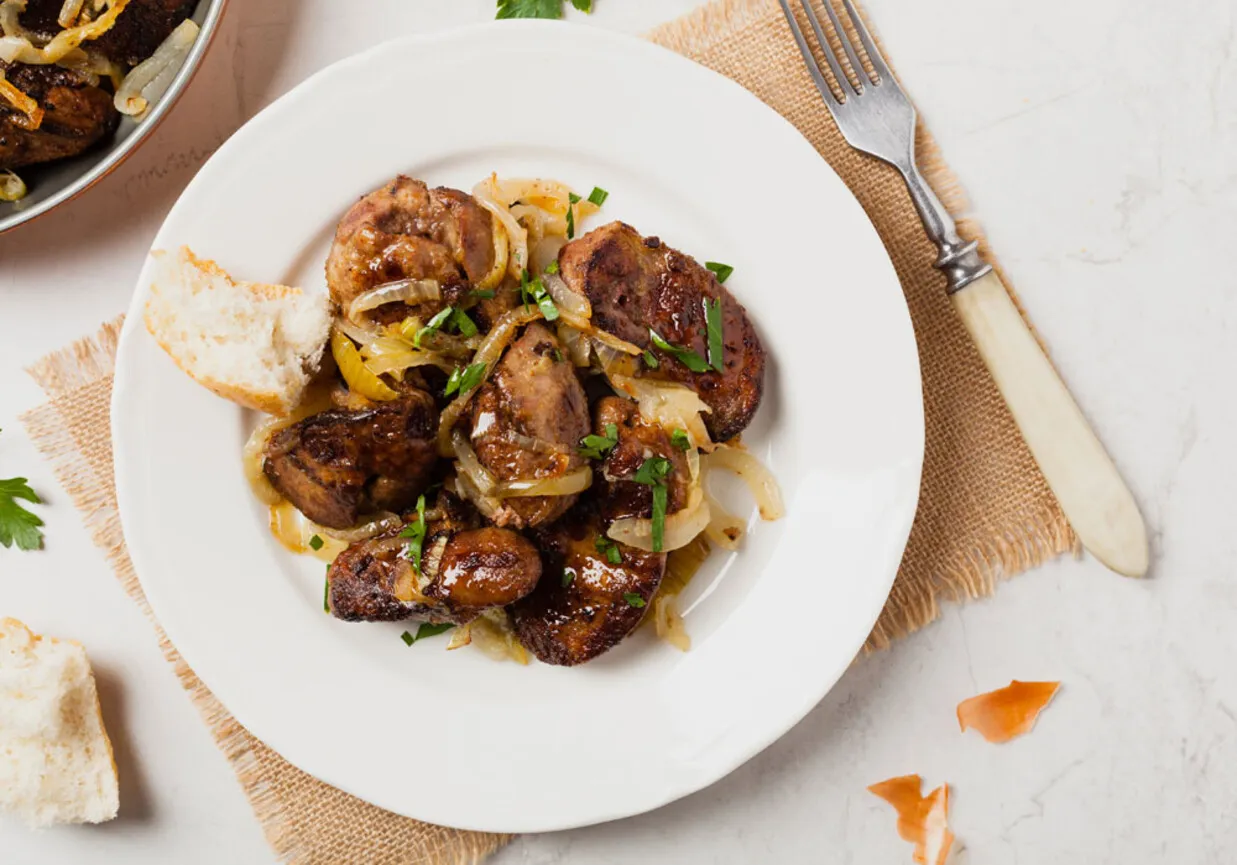 Smażona wątr&oacute;bka drobiowa z cebulką na białym talerzu, podana z chlebem. Idealna na szybki obiad, gdy zastanawiasz się, jak długo gotować wątr&oacute;bkę drobiową.