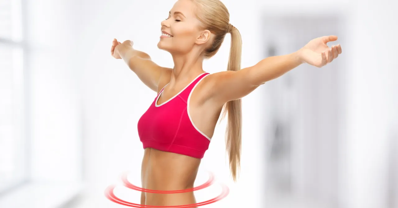 Szczęśliwa kobieta w sportowym topie, z ramionami rozłożonymi na boki, symbolizuje sukces w odchudzaniu. Jej uśmiech i lekkość to efekt przemiany, o kt&oacute;rej przeczytasz na blogu 