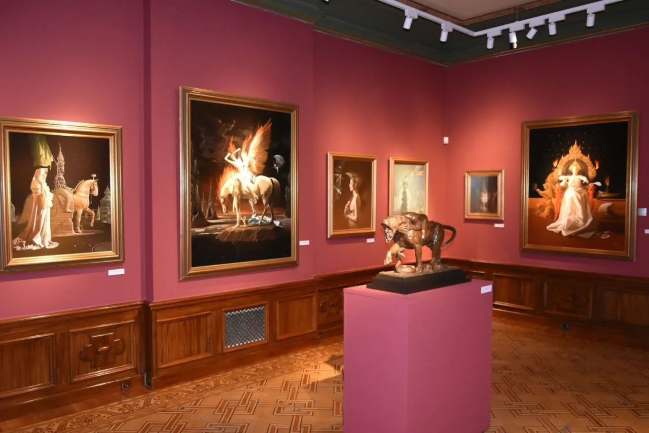 W muzeum sztuki fantastycznej obrazy przedstawiają skrzydlatą postać na koniu w ogniu, kobietę w białej sukni i rzeźbę tygrysa.