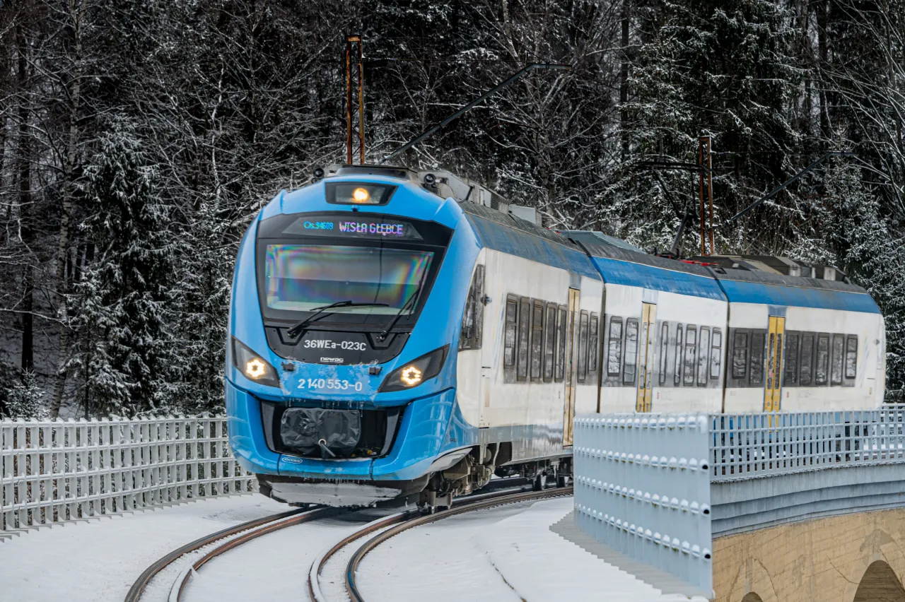 Błękitny pociąg mknie przez ośnieżony las. Od kiedy pociągiem do Wisły, zimowa podr&oacute;ż nabiera magii.