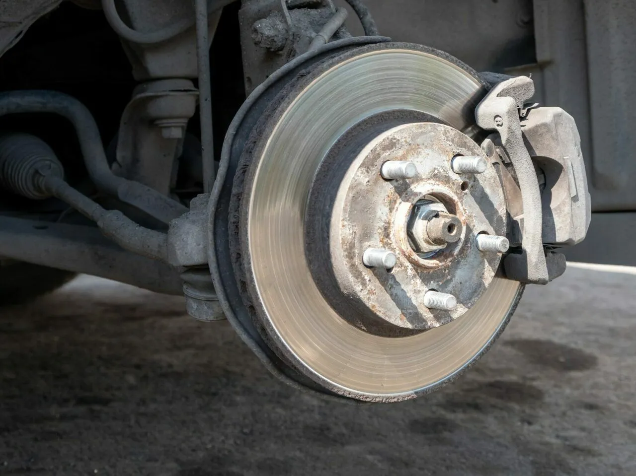 Widok na tarczę hamulcową i zacisk. Pokazuje, jak ściągnąć tarcze hamulcowe, odsłaniając śruby mocujące.