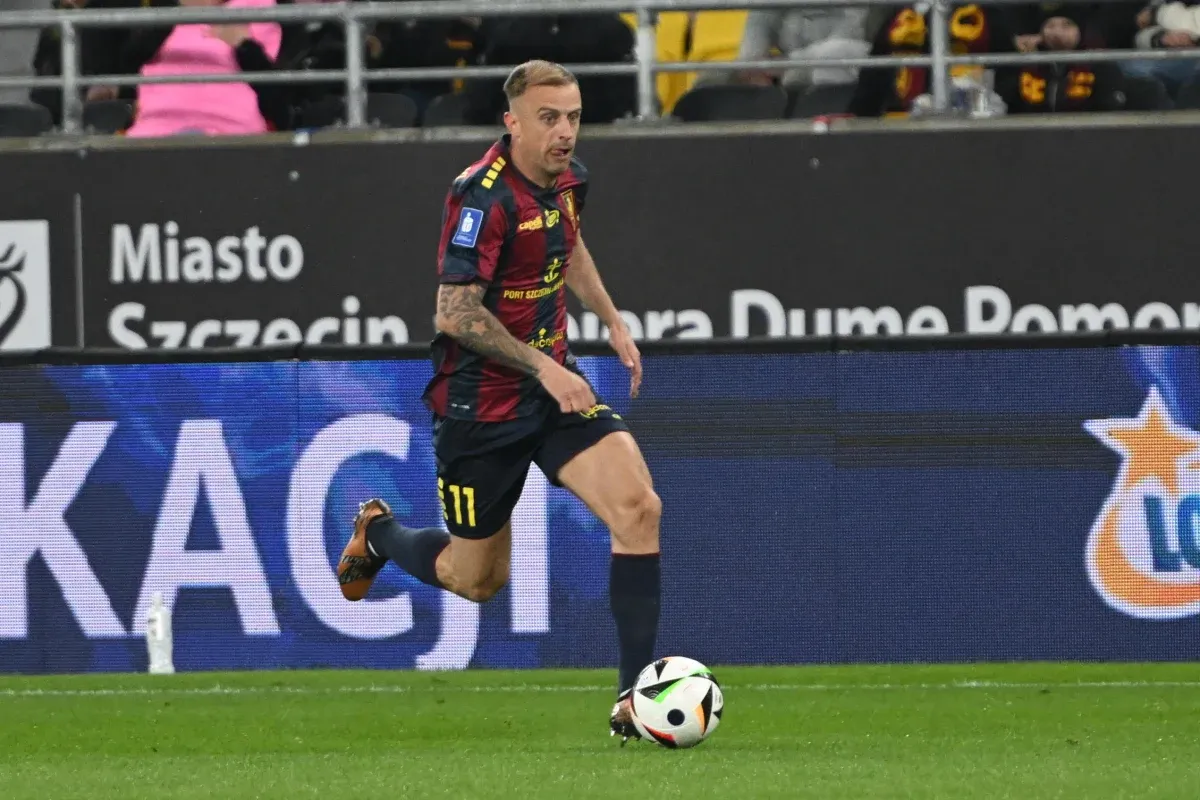 Piłkarz w koszulce z numerem 11 biegnie z piłką. Ciekawe, ile zarabia Grosicki w Pogoni, grając tak dynamicznie.