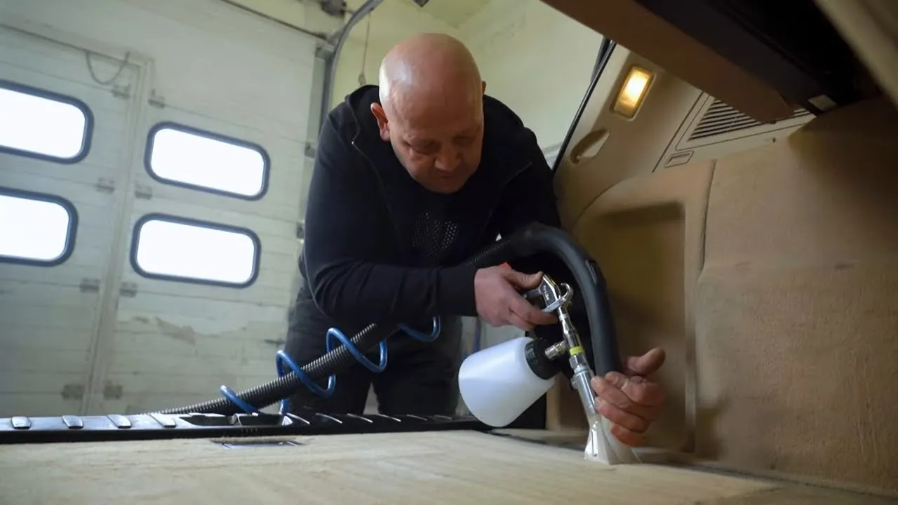 osoba używająca kompresora do czyszczenia wnętrza samochodu