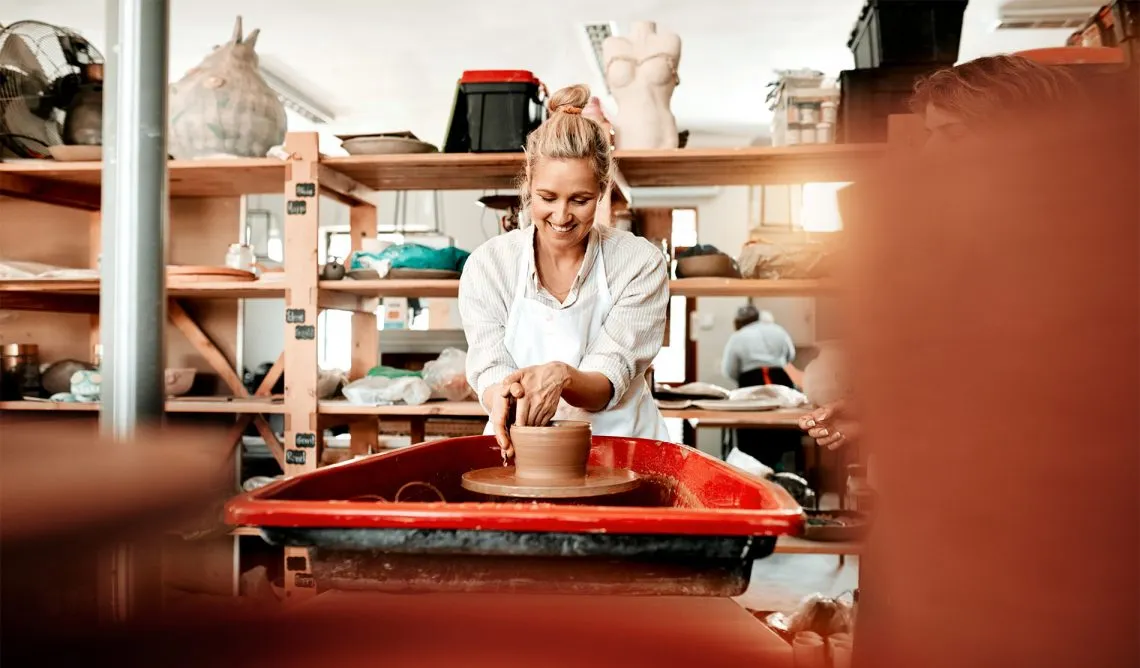 osoba lepiąca z gliny na warsztatach ceramicznych w jasnej pracowni