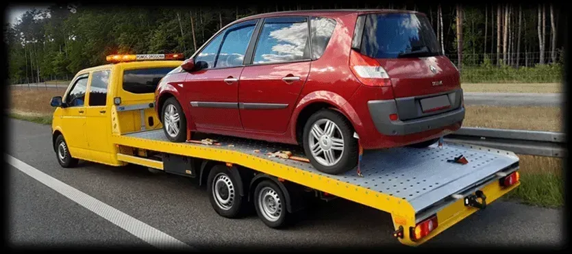 Laweta holująca samochód osobowy na drodze