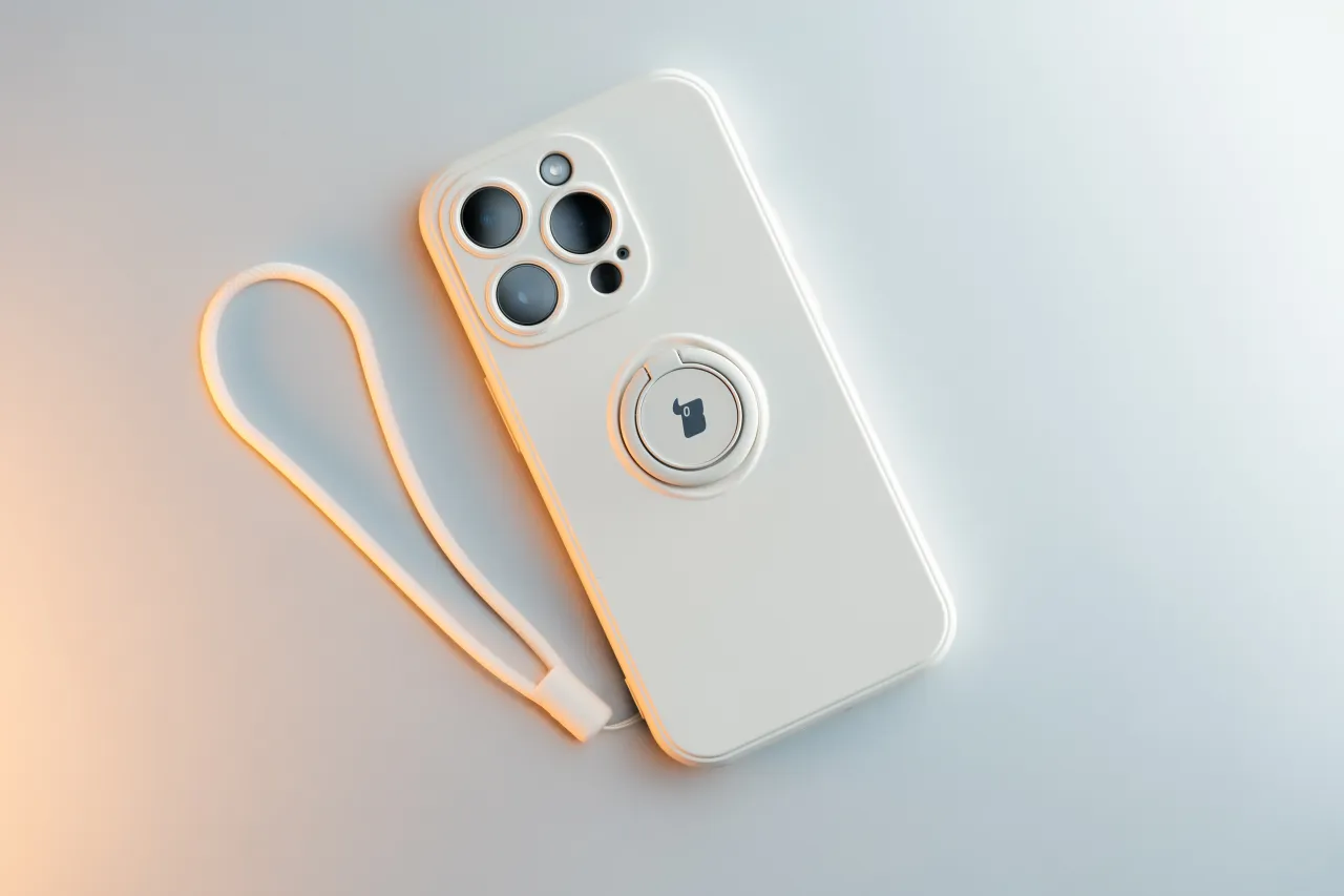 Białe etui na telefon z uchwytem i smyczką. Dowiedz się, jak wyczyścić etui na telefon, by wyglądało jak nowe.